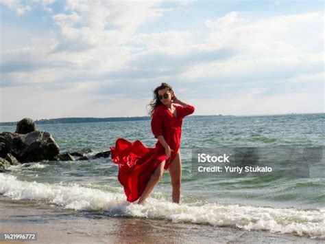 Barefoot Woman With Black Hair In A Red Dress Fluttering In The Wind On