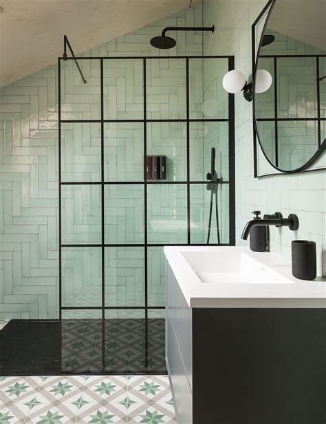 A Bathroom With Green Tiled Walls And Flooring Next To A White Sink