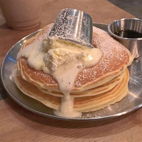 A Stack Of Pancakes With Butter And Syrup Being Poured Onto Them On A