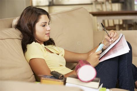 Adolescente Que Senta Se Em Sofa At Home Doing Homework Foto De Stock