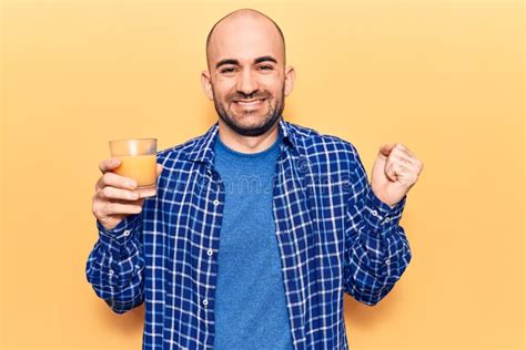 Young Handsome Bald Man Drinking Glass Of Healthy Orange Juice