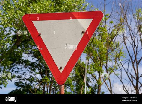 Close Up Of Give Way Road Sign Red And White Triangle Green Trees And