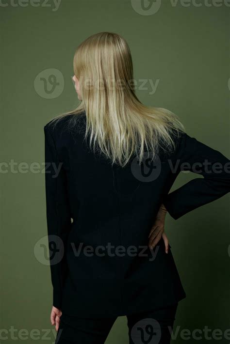 Elegant Strict Blonde Girl Turns Her Back To The Camera Looks Away Posing On A Green Background