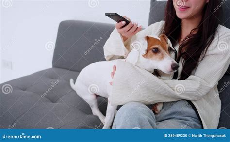 Beautiful Young Asian Woman And Dog Sitting On Sofa Watching Movie On