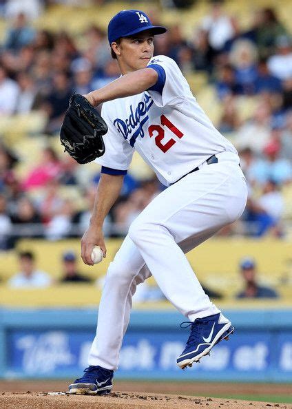 A Baseball Player Pitching A Ball On Top Of A Field In Front Of A Crowd