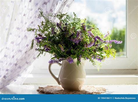 Un Ramo De Flores Silvestres En Una Jarra Blanca Junto A La Ventana