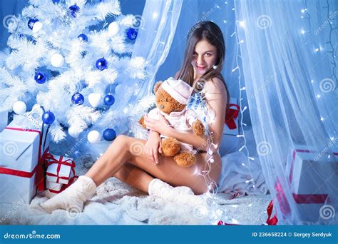 Christmas Girl With Toy Near Christmas Tree With Lights In Blue And White Lingerie Stock Photo