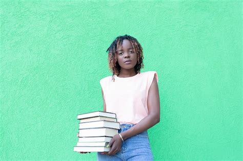 Una Hermosa Mujer Afroamericana Sostiene Una Pila De Libros Sobre Un