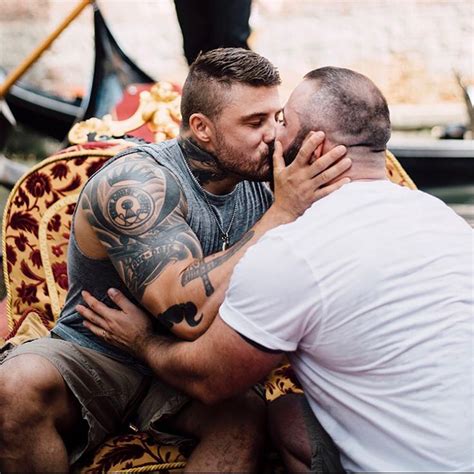 Two Men Are Kissing Each Other While Sitting On A Chair In Front Of A