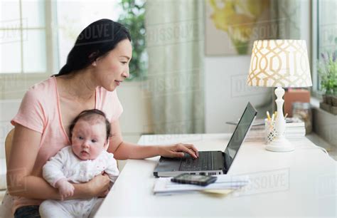 Asian Mother With Baby Working From Home Stock Photo Dissolve