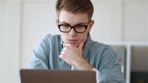 Thoughtful Guy Holding Hand On Chin Working At Home Office Stock