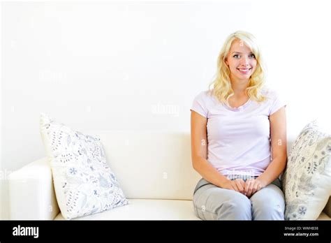 Pretty Blonde Woman Sitting On Couch At Home Smiling Stock Photo Alamy