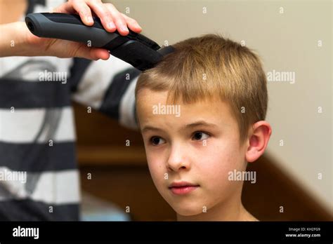 Hairdresser Is Cutting Hair Of A Child Boy In Barber Shop Stock Photo