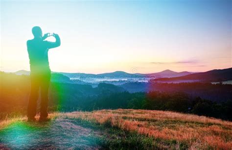 Man Hold Phone Above Head And Takes Photos Of Morning Misty Landscape