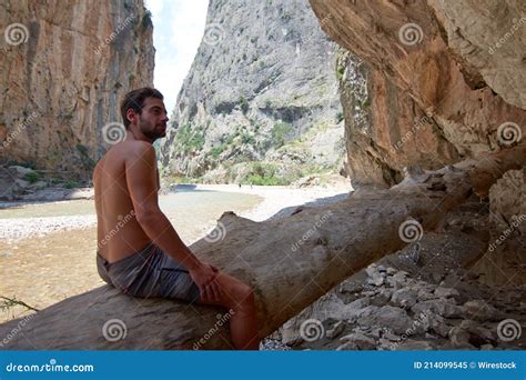 Closeup Of A Half Naked Caucasian Man Sitting On A Big Wood Log Under A