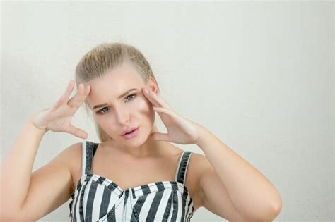 Coole junge blonde Frau mit perfektem Make up posiert über einer weißen Wand Platz für Text
