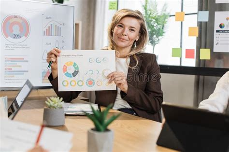 Focused Caucasian Senior Woman Sitting At Desk With Paper Report In Her