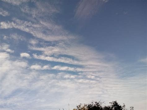 The Sky Is Filled With Clouds And Some Trees In The Foreground As Well