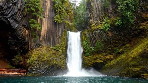 Waterfalls Pouring On River Between Green Trees Algae Covered Rocks