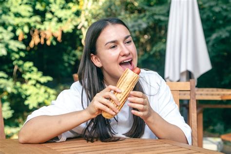 Une Jeune Femme Mange Un Hot dog Sur Une Terrasse De Café Photo Gratuite
