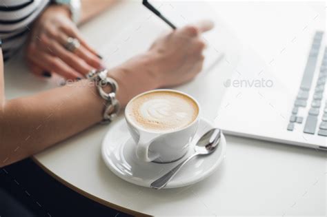Hot Art Latte Coffee In A Cup On Wooden Table And Coffee Shop Blur Background With Woman S Hands