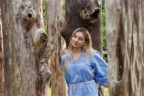 Portrait Of A Pretty Blonde In A Blue Dress Between Big Dry Tree Trunks Stock Photo Image Of