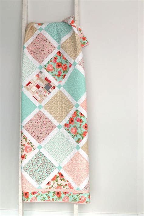 a colorful patchwork quilt hanging on a white coat rack in a room with wood flooring