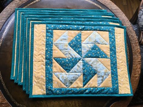 Four Quilted Placemats Sitting On Top Of A Wooden Table