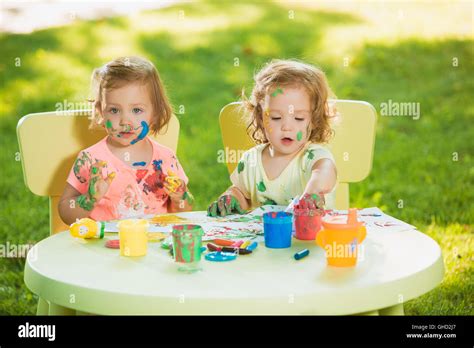 Two Year Old Girls Painting With Poster Paintings Together Against