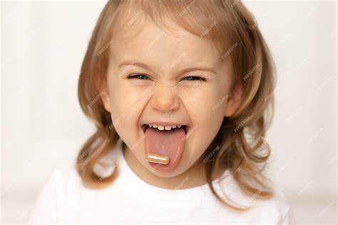 Muchacha Del Niño Divertido Con La Píldora En La Lengua Tomando