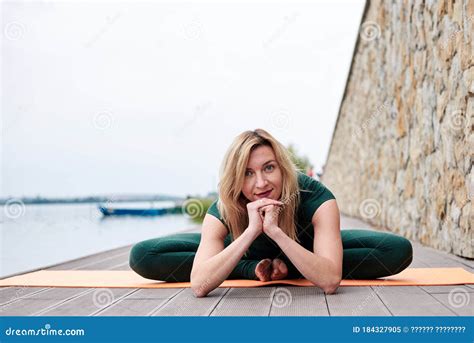 Young Blond Woman Wearing Green Overall With Bare Feet Doing Yoga Pose