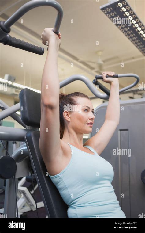 Fit Brunette Using Weights Machine For Arms At The Gym Stock Photo Alamy
