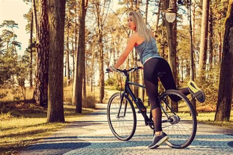 Femme blonde sexy sur un vélo dans un parc d été Photo Gratuite