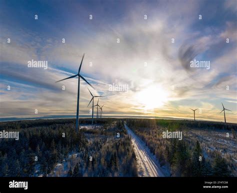 Aerial Scenic Photo Over Forest Winter Road With Windmills Standing In Row At The Left Side In