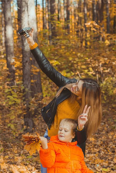 Son And Mother Are Taking Selfie On Camera In Autumn Park Single