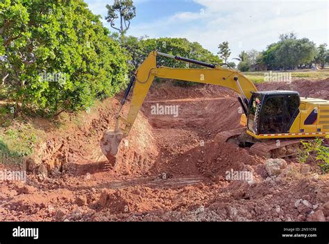 Backhoe bucket digging the soil at agriculture farm to make pond. Crawler excavator digging at ...