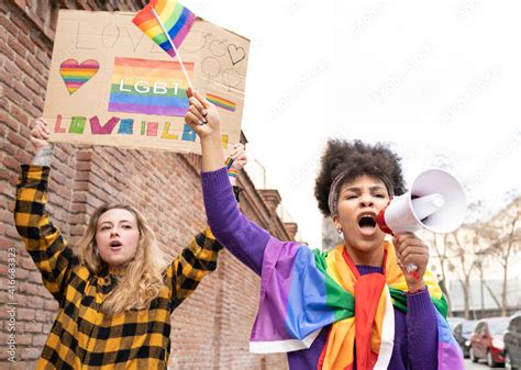 Two Multi Ethnic Women Celebrating Gay Pride Event Wearing The Rainbow Flag Symbol Of The Lgbt