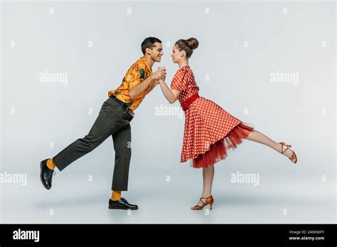 Stylish Dancers Holding Hands While Dancing Boogie Woogie On Grey