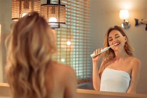 Premium Photo Beautiful Blonde Woman Brushing Her Teeth Using Electric Toothbrush Having Fun