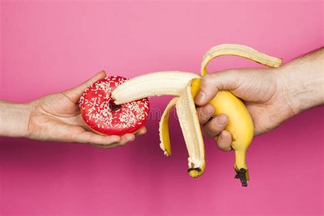 Erotic Banana And Donut In The Hands As A Symbol Of The Penis And Vagina Isolated On A White
