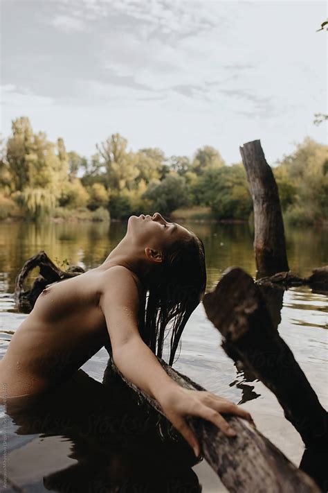 Nude Girl Leaning Over Tree In River Water Looking Up At The Sky By Stocksy Contributor