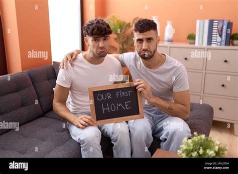 Homosexual Gay Couple Holding Blackboard With First Home Text Depressed