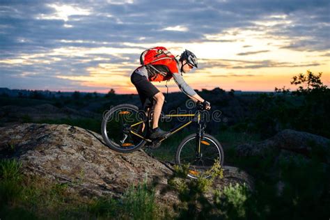 Cyclist Riding The Bike Down Hill On Mountain Rocky Trail At Sunset