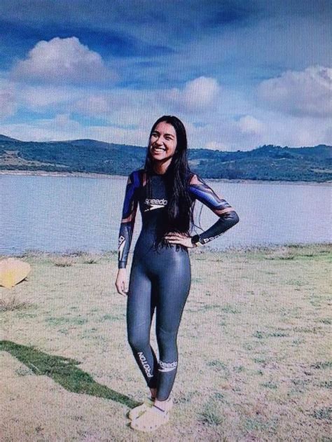 A Woman In Wetsuit Standing Next To A Body Of Water