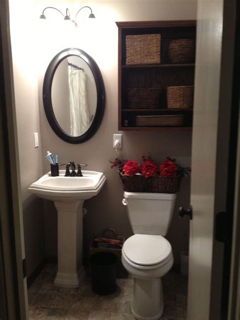 a white toilet sitting next to a sink in a bathroom under a mirror and a wooden shelf