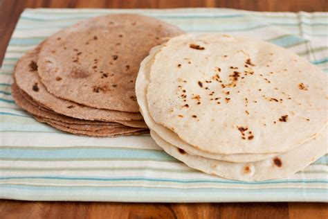 Three Tortillas Are Sitting On A Striped Cloth Next To A Wooden Table Top