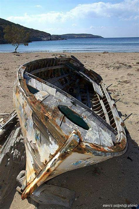 An Old Wooden Boat Sitting On Top Of A Sandy Beach Next To The Ocean