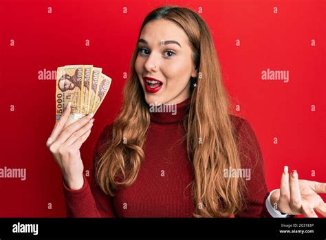 Jeune femme blonde détenant billets de forint hongrois célébrant la réussite avec un