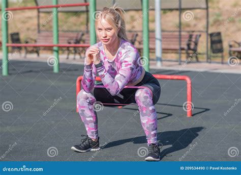 Beautiful And Athletic Blonde Girl Doing Squats On The Street Sports