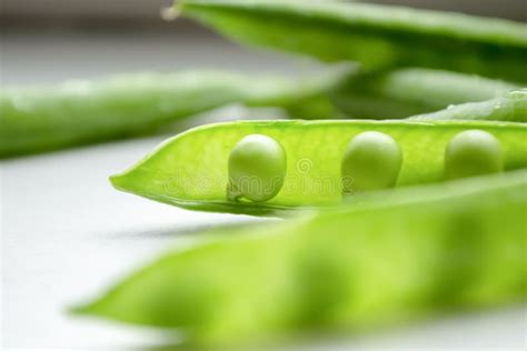 Green Peas On The Table On A White Background Is An Open Pod Of Green